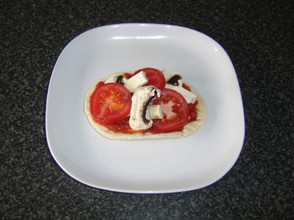 Tomato and mushroom slices are laid atop the tomato sauce