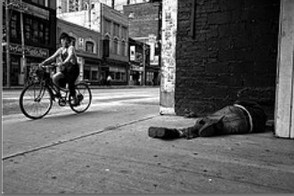 Girl On Bicycle Looks At Man Sleeping In Alley