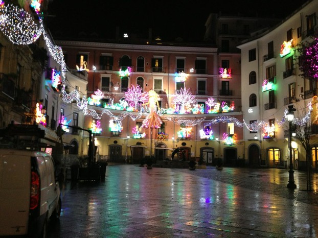 On a rainy January night, the lights reflect a colorful rainbow on a Salerno piazza.
