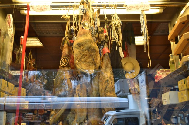 Prosciutto hams hanging in a deli window in Rome, Italy