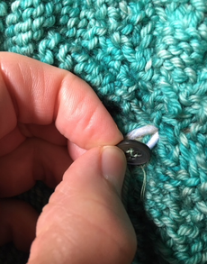 Pull the loop through and attach to a button sewn inside the hat.