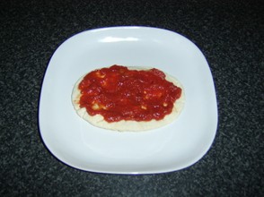 Tomato sauce is spread on the pitta bread