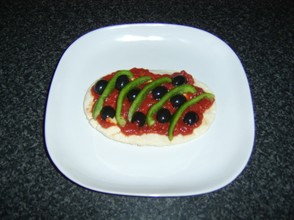 Green bell pepper and olives are added to the pizza