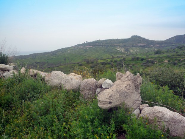 Calabrian panorama of mountainous landscapes, stone fence decorated with horse head sculpture, and sea in the background