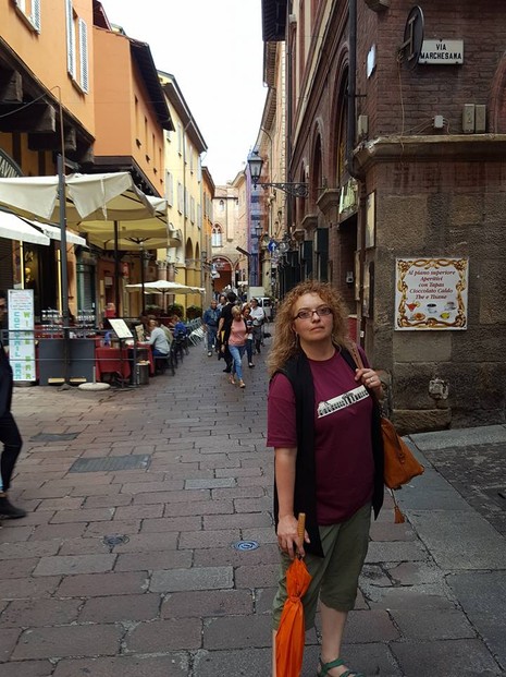 Markets and cafes on a narrow street in Bologna's historic center