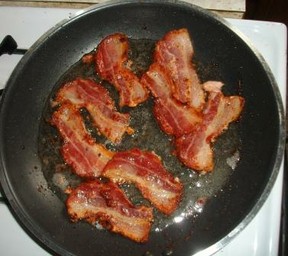 Partially cooked bacon in frying pan